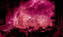 a group of people are standing in front of a large purple explosion in a city .