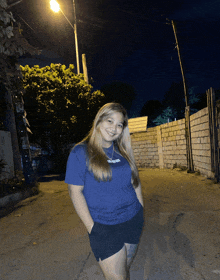 a woman wearing a blue t-shirt that says ' adidas ' on the front