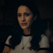 a woman wearing a white t-shirt and a necklace with the word kepler on the bottom