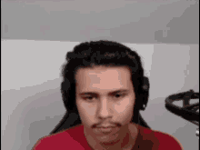 the man is wearing headphones and a red shirt .