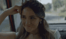 a woman with a braided headband is smiling and looking out the window