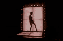 a skeleton is standing on a stage in front of a pink wall .