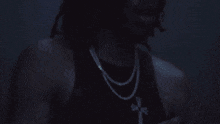 a man in a black tank top is smoking a cigarette in a dark room