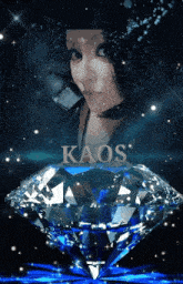a woman is standing next to a large diamond with kaos written on it