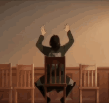 a man is sitting in a chair with his hands in the air