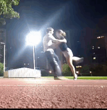 a man holds a woman in his arms on a track at night