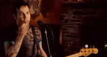a man is playing a guitar and singing into a microphone while smoking a cigarette .