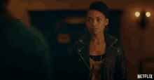 a woman in a leather jacket stands in front of a netflix ad