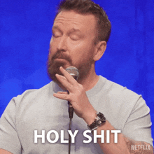 a man speaking into a microphone with the words holy shit written below him