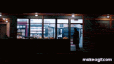a man in a black coat is standing in a grocery store looking at shelves and a make a gif.com button