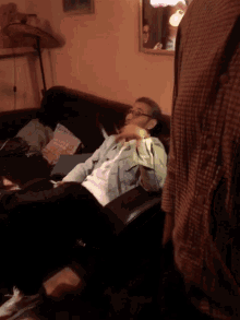 a man wearing glasses sits on a couch in a living room