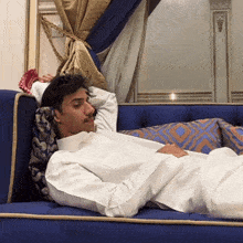 a man is laying on a blue couch with his head on a pillow