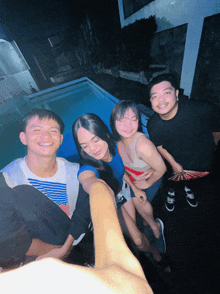 a group of young people are posing for a picture in front of a swimming pool