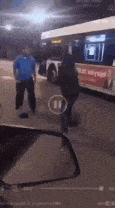 a man in a blue shirt is standing next to a woman in a black jacket in front of a bus