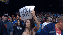 a woman holding a sign that says wtf in front of a crowd