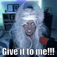 a woman in a white wig with horns and a crown says give it to me