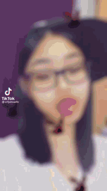 a blurry picture of a woman with glasses and a lollipop in her mouth