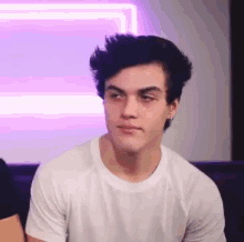 a young man is sitting on a couch wearing a white t-shirt .