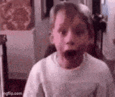 a young boy is making a surprised face in a room .