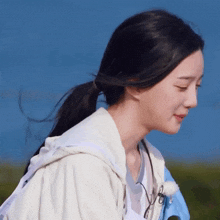 a woman wearing a white jacket with a hood and a ponytail