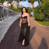 a woman in a black dress is walking down the street