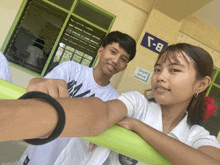 a boy and a girl are posing for a picture in front of a blue sign that says b-1