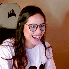 a woman wearing glasses and a white shirt with a corsair logo on the back of her chair