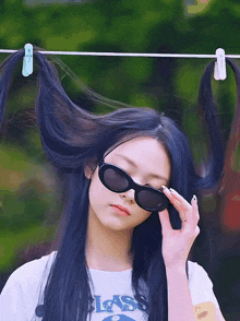 a girl wearing sunglasses has her hair hanging from a clothes line