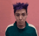 a man with purple hair is wearing a green jacket and looking at the camera .
