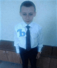 a boy wearing a white shirt and black tie has a sticker on his shirt that says b