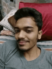 a young man with a beard is smiling while laying on a bed