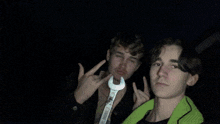 two boys are making funny faces and one has a green shirt on