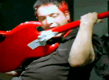 a man in a black shirt is playing a red electric guitar