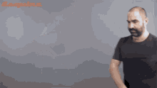 a bald man with a beard is wearing a black t-shirt with esquire written on the bottom