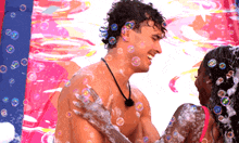a man and a woman are covered in soap bubbles and the man is smiling