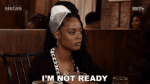 a woman is sitting at a table with a drink and says " i 'm not ready "
