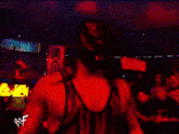a man in a red and black wrestling outfit stands in front of a crowd of people
