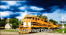 a yellow train with the letter t on the front is on the tracks