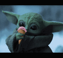 a baby yoda holding an ice cream cone in his hand