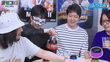 a group of people are playing a game with a coca cola bottle in the foreground