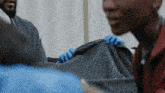 a person wearing blue gloves is holding a piece of blanket