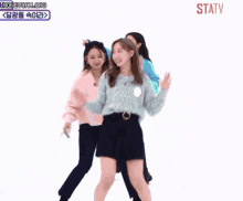 a group of girls are dancing in front of a sign that says statv on it