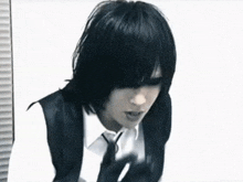 a man with black hair and a white shirt is wearing a vest and tie .