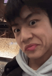 a young man is making a funny face while wearing a white hoodie .