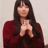 a woman in a red sweater is holding a picture of herself in her hands