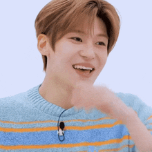 a young man wearing a blue and orange striped sweater and a microphone