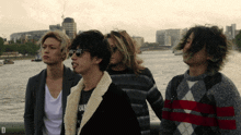 a group of young men standing in front of a body of water with the letter d visible