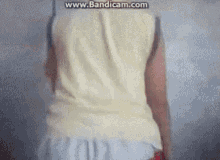 a person wearing a white tank top and white shorts is standing in front of a wall .