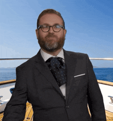 a man in a suit and tie is standing on a boat in the ocean