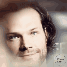 a close up of a man 's face with a photo lab logo in the background